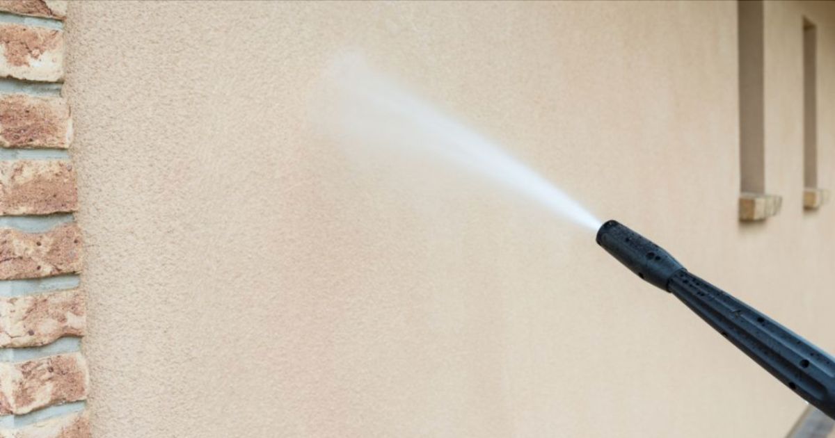 Een vochtbestrijder is de gevel met een spuit aan het impregneren met een waterafstotend middel.