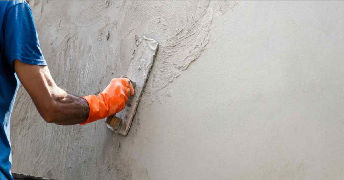 Een vakman is cementpleister op een gevel aan het aanbrengen