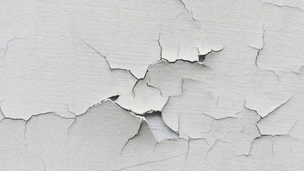 Vergevorderde barsten in een crepi gevel. De laag crepi laat los van de ondergrond.