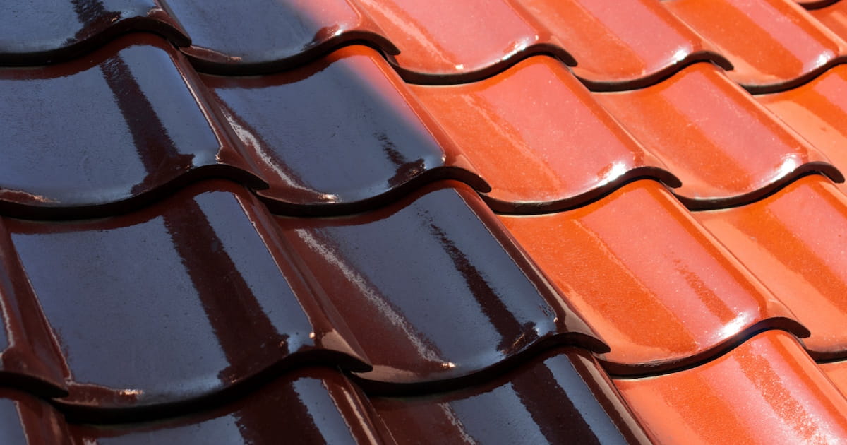 Een close-up van rode dakpannen met een engobe afwerking, waardoor de pannen een glanzende uitstraling krijgen