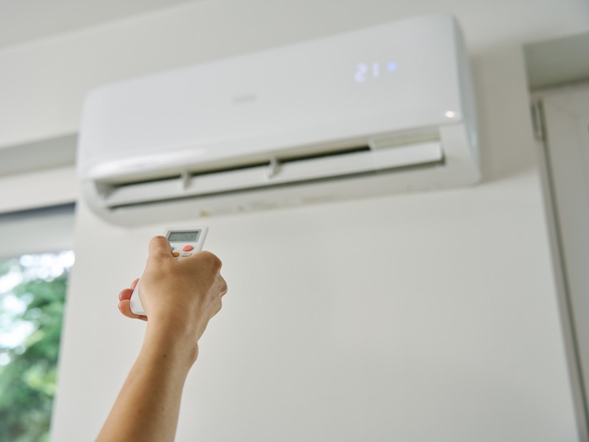 hand met afstandsbediening stelt de airco in voor verwarmen