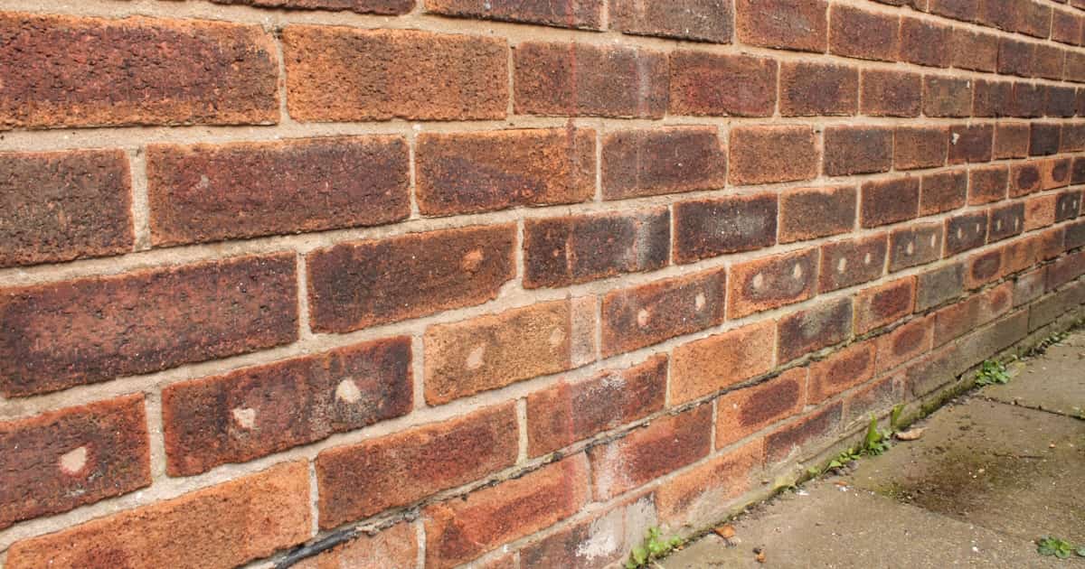 Gevulde boorgaten in een bakstenen muur. De bakstenen zijn rood van kleur