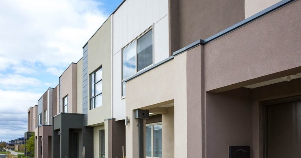 Een aantal rijwoningen waarvan de gevels verschillende kleuren hebben. Op de achtergrond een blauwe lucht.