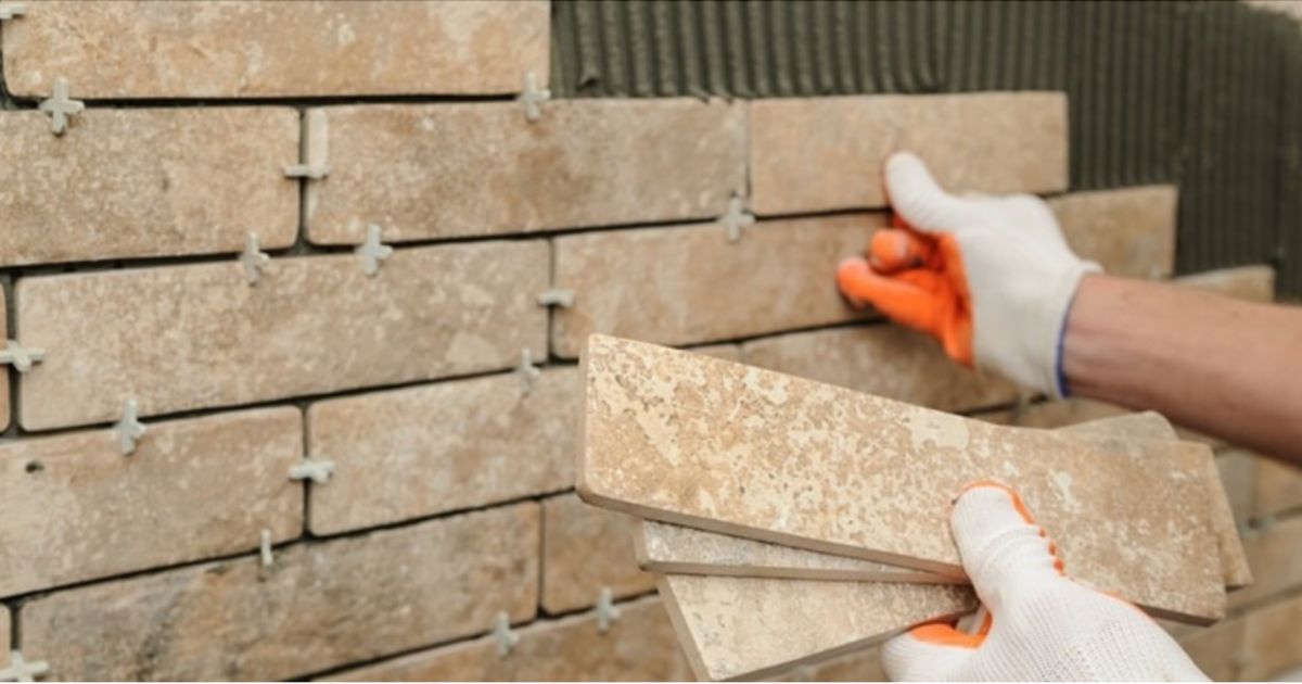 Een vakman is een buitenmuur aan het heropbouwen na een nieuwe isolatie