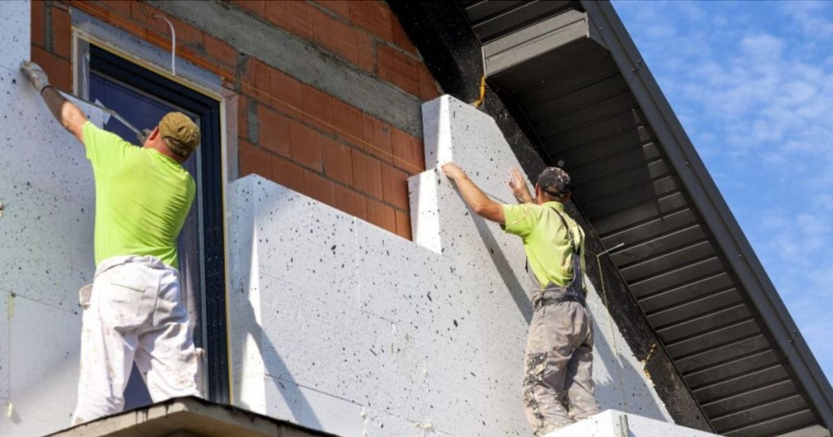 Twee vakmannen zijn een buitenmuur opnieuw aan het isoleren