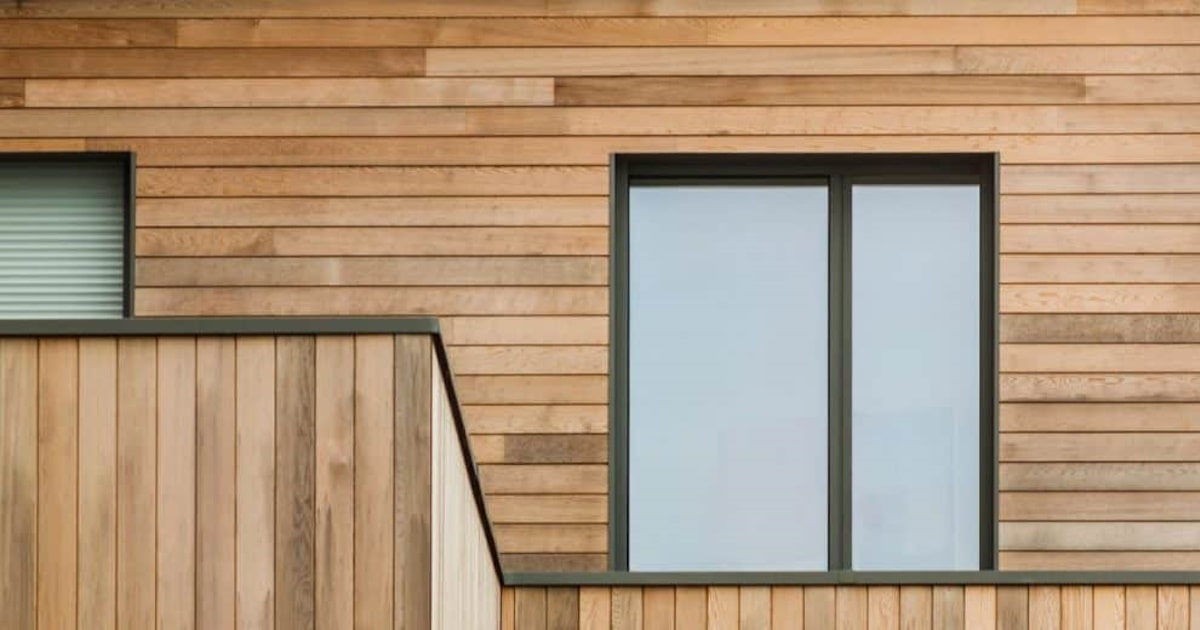 Verticale en horizontale gevelbekleding worden gecombineerd. Het hout is licht van kleur en steekt mooi af tegen de donkere kozijnen.