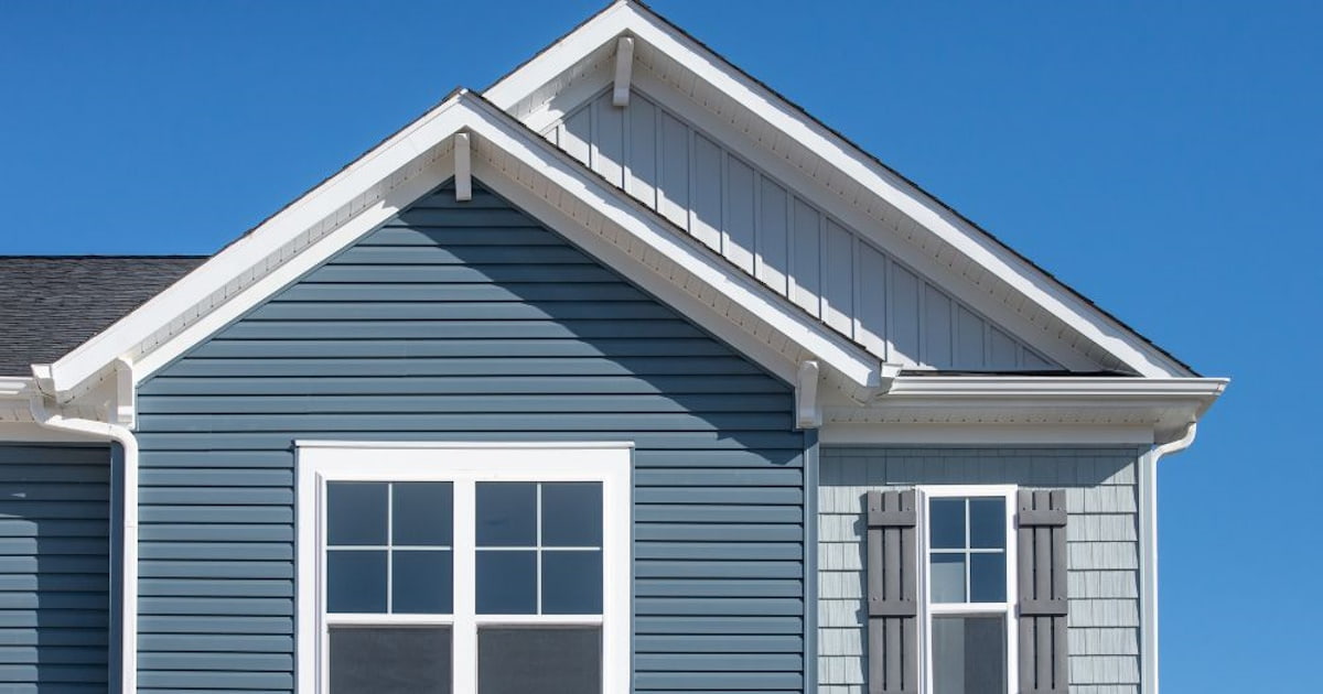 Een woning met sidings als gevelbekleding. De sidings zijn gemaakt van composiet en hebben verschillende blauwe en witte tinten gekregen.