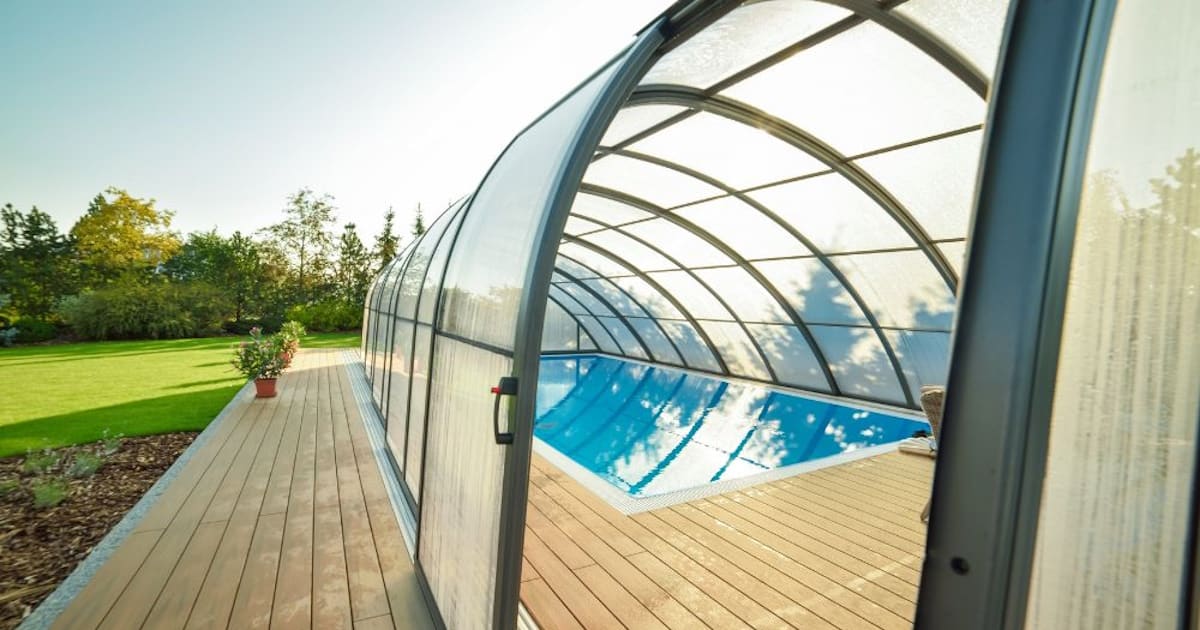 Een zwembad wordt overdekt door kunststof sidings. De overkapping is in de vorm van een boog.