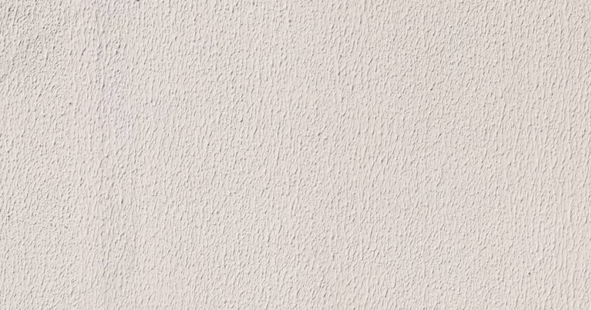 Een close-up van een lichte sierpleister gevel. De structuur in de gevelpleister is goed zichtbaar.