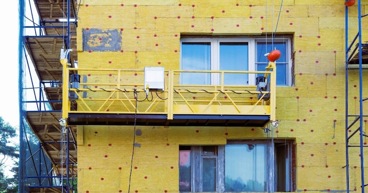 Het isoleren van een gevel is in gang. De isolatie is al tegen de gevel geplaatst, de afwerking laat nog op zich wachten.