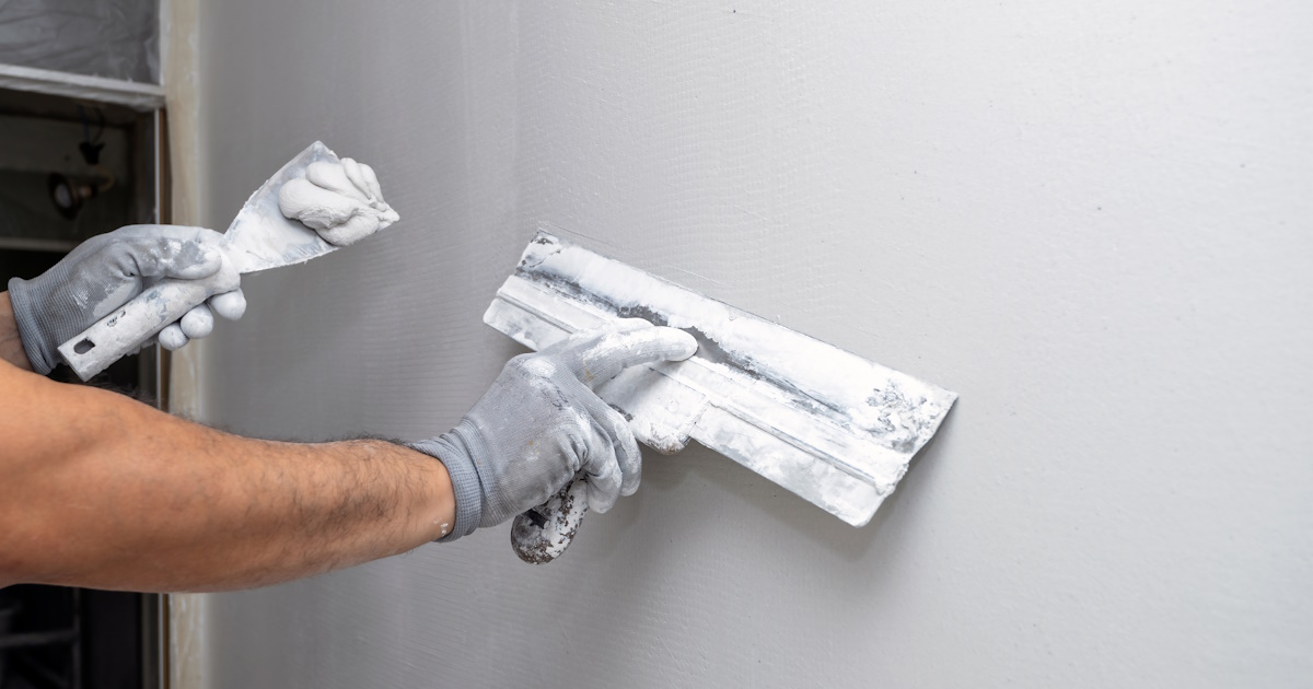 Een stukadoor stuct over glasvezelbehang heen.