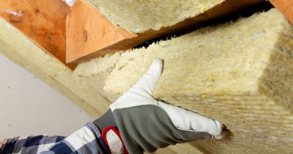 Een expert plaats glaswol dakisolatie tussen de dakconstructie