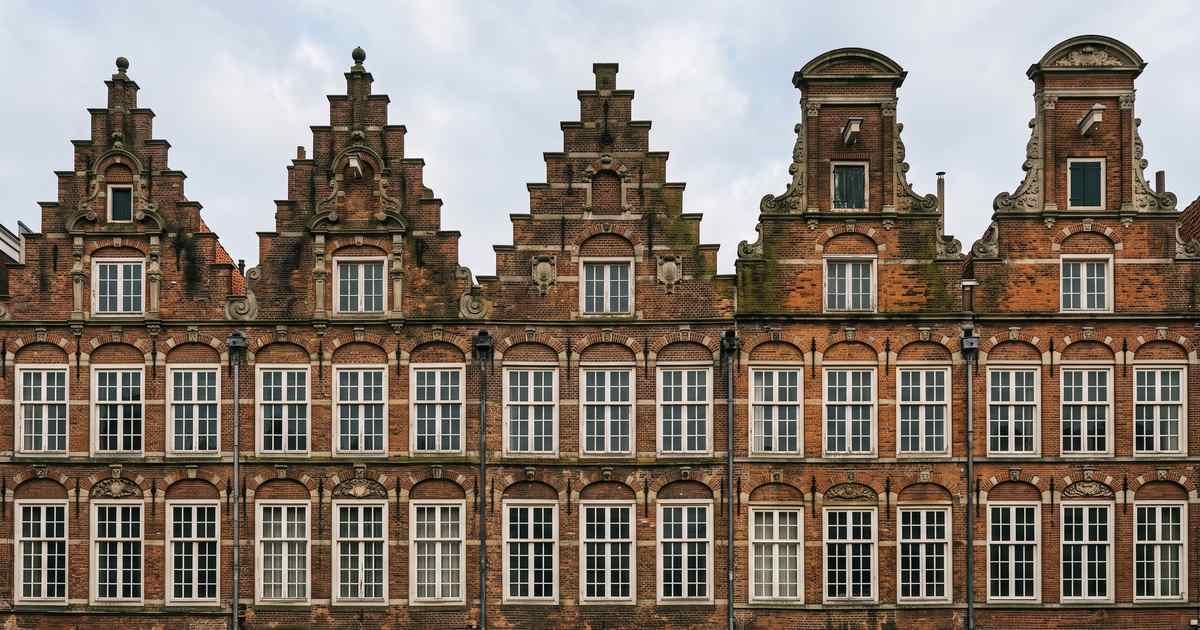 Rij historische trap- en klokgevels in een beschermd stadsgezicht met verweerd metselwerk en groene aanslag