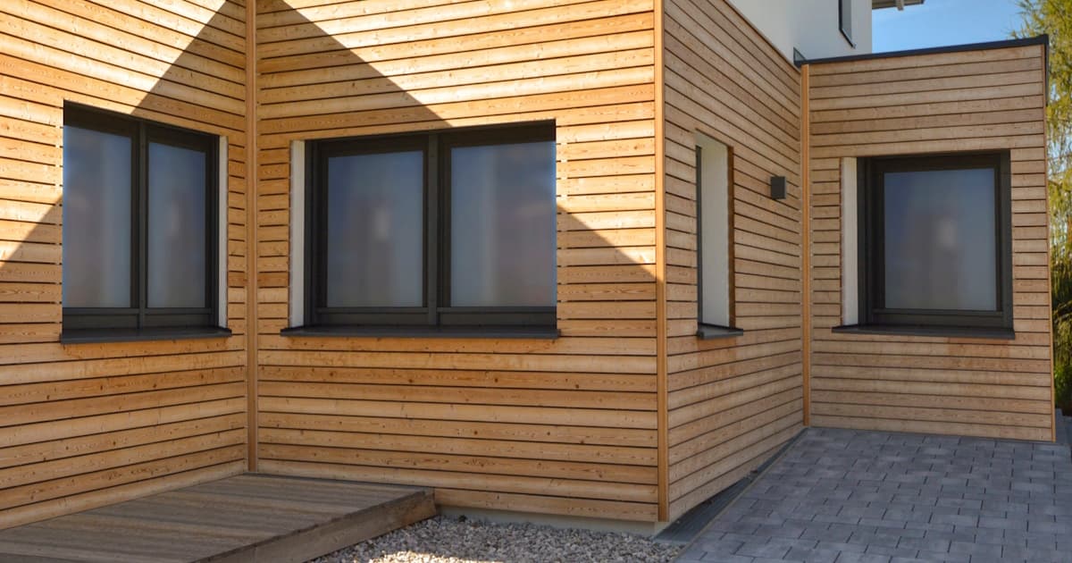 Moderne woning met combinatie van wit pleisterwerk en horizontale houten gevelbekleding met donkere raamkozijnen.