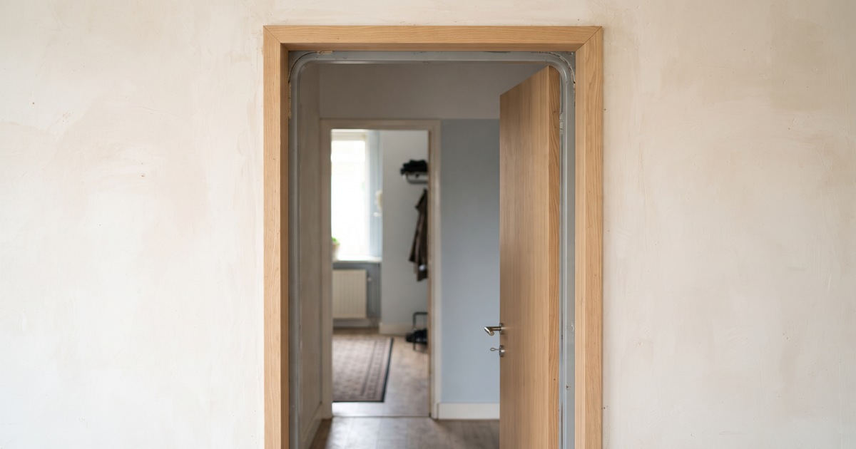 Houten renovatiekader over een oud stalen deurkozijn, met de grijze stalen rand nog zichtbaar