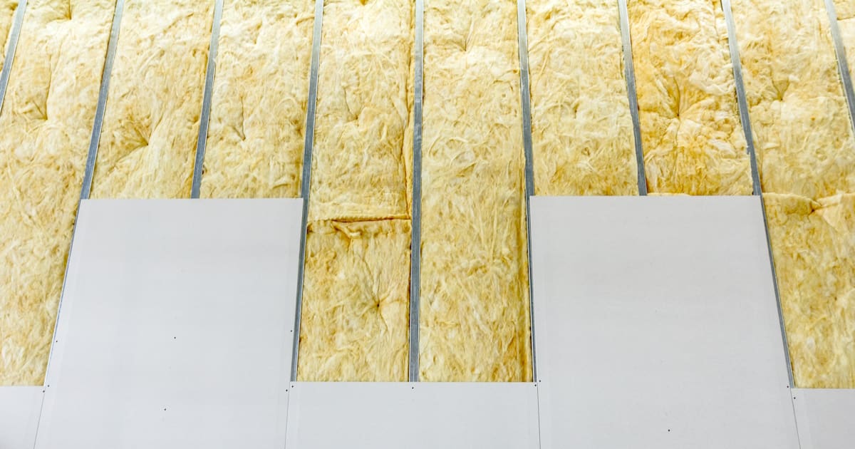 Stroken glaswol zijn tussen een metalen raamwerk geplaatst. De isolatie wordt afgewerkt met gipsplaten