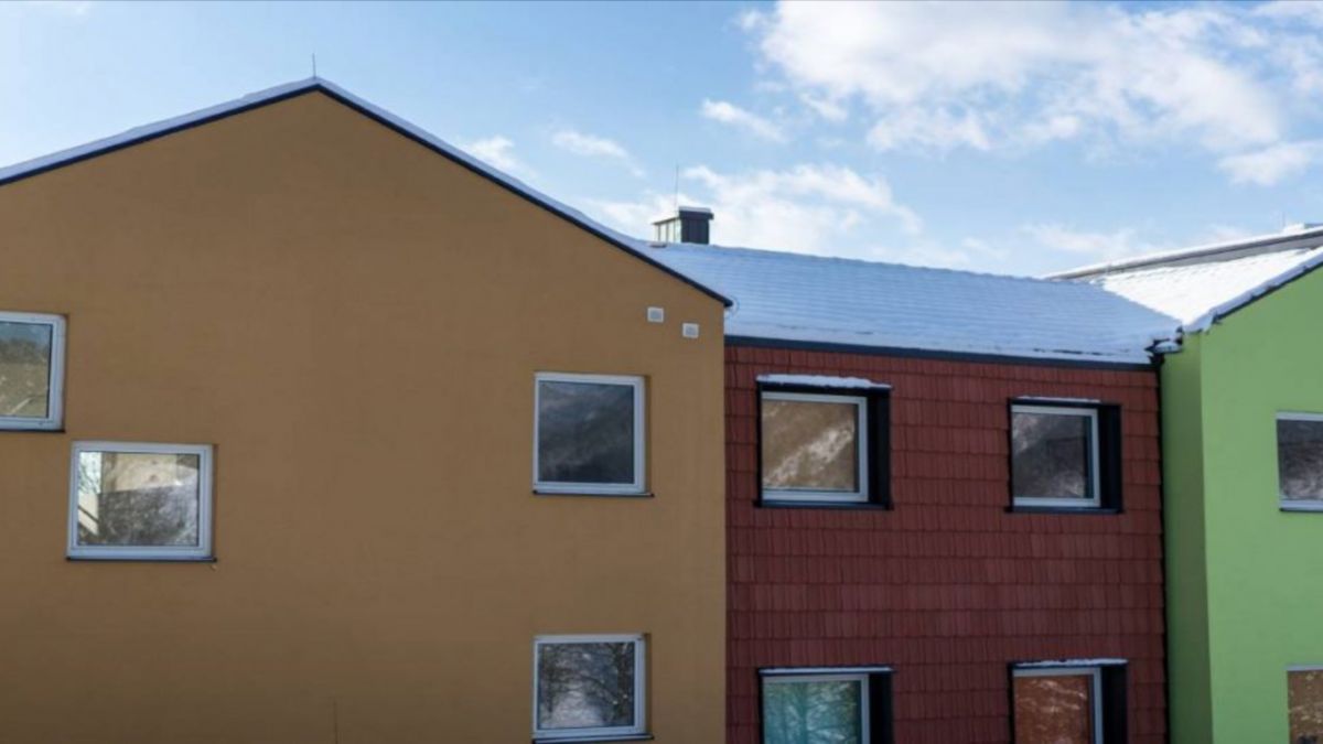 Drie huizen met verschillende kleuren gevels zijn bedekt met gevelpleister