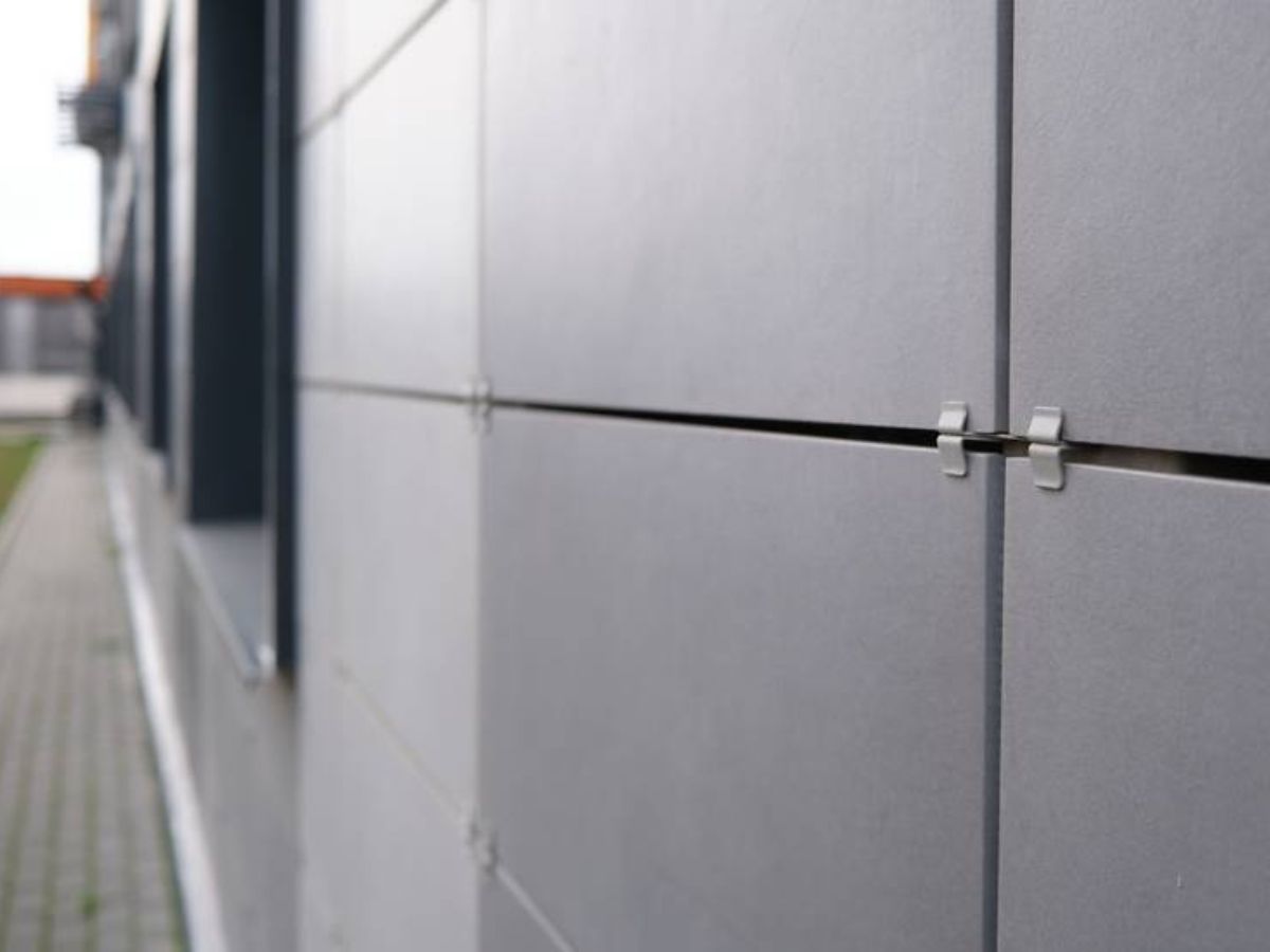 Detail van keramische gevelbekleding met klembevestiging en strakke voegen aan de buitenmuur.