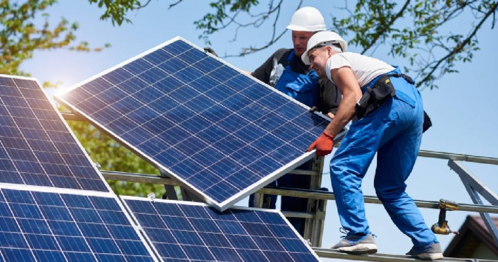 Twee mannen installeren zonnepanelen op het dak van een woning.