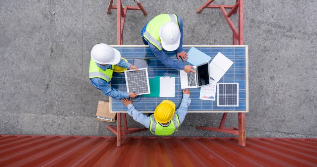 Drie mannen berekenen met een laptop de nodige capaciteit voor de thuisbatterij van een zonnepaneel.