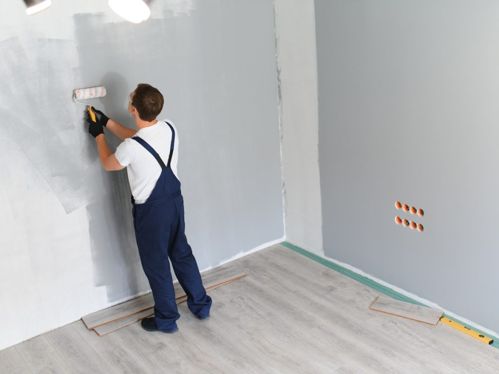 Een schilder verft de muur met een pluizige verfroller