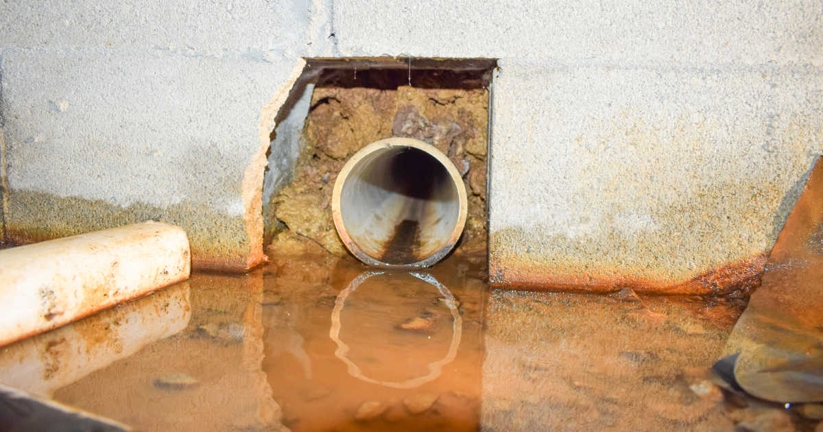 Kruipruimte met een laag water en leiding in muur