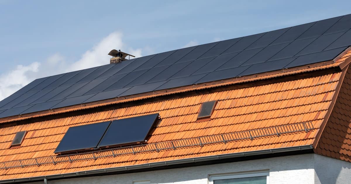 Een oranje mansardedak met de kenmerkende knik halverwege het dakschild. Op de dakpannen zijn zonnepanelen geplaatst.