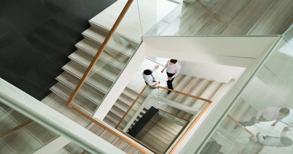 meerdere verdiepingen van dubbele kwartslagtrappen met houten leuningen en glazen balustrades