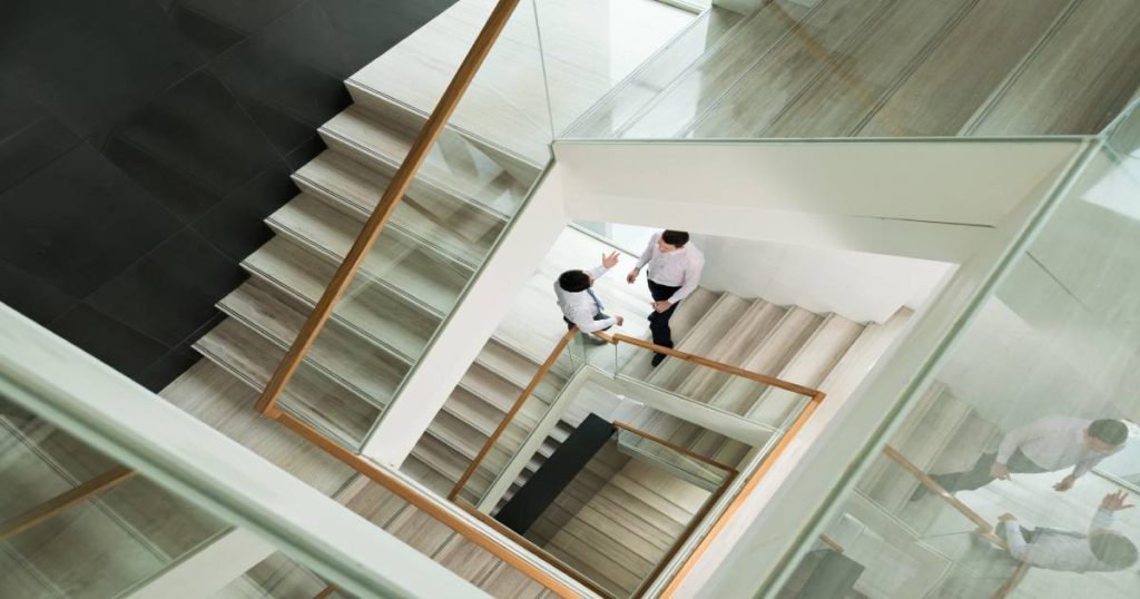 meerdere verdiepingen van dubbele kwartslagtrappen met houten leuningen en glazen balustrades