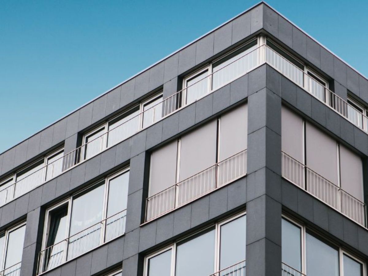 Modern appartementengebouw met kunststof gevelpanelen en grote ramen met balkonhekwerken.