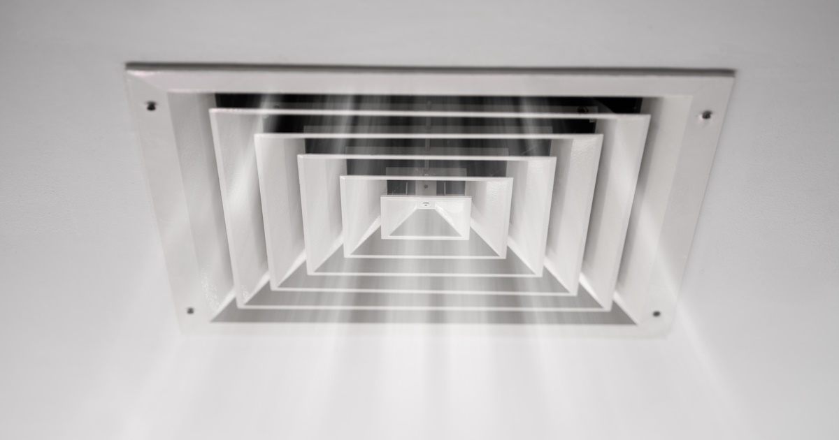Een ventilatierooster waar frisse lucht doorheen blaast. Het rooster is vierkant en wit.