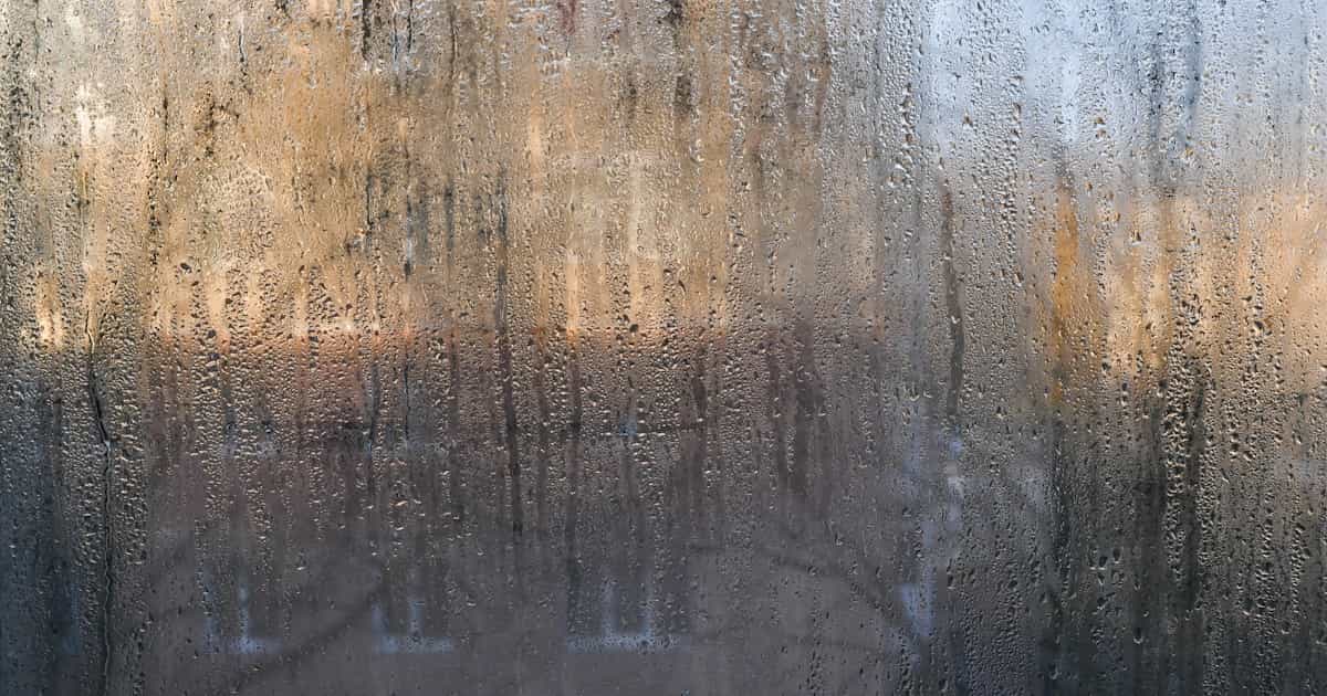 Een beslagen raam. Condens drupt naar beneden. 