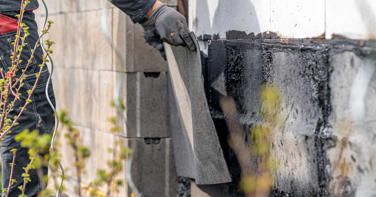 Een muur wordt van buitenaf waterdicht gemaakt met een waterwerende laag