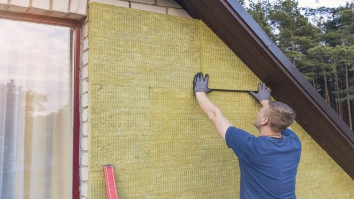 Een isolatiespecialist is de buitenmuren van een huis aan het isoleren.