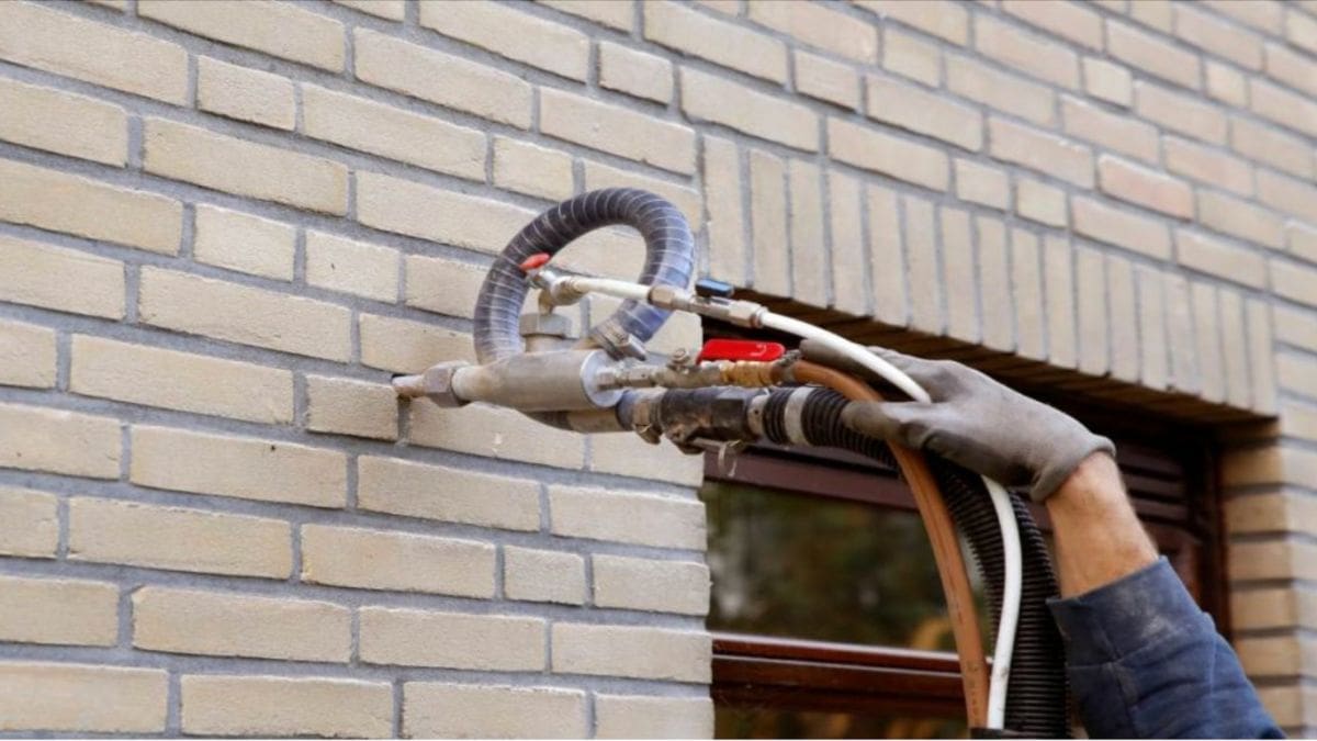 Een isolatie-expert is een spouwmuur aan het opvullen met isolatiemateriaal.