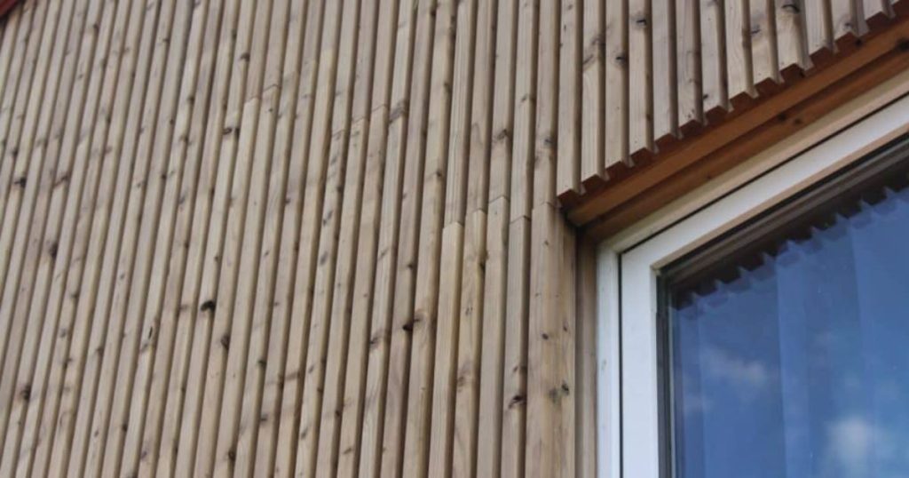 Detail van verticale open houten gevelbekleding naast raam