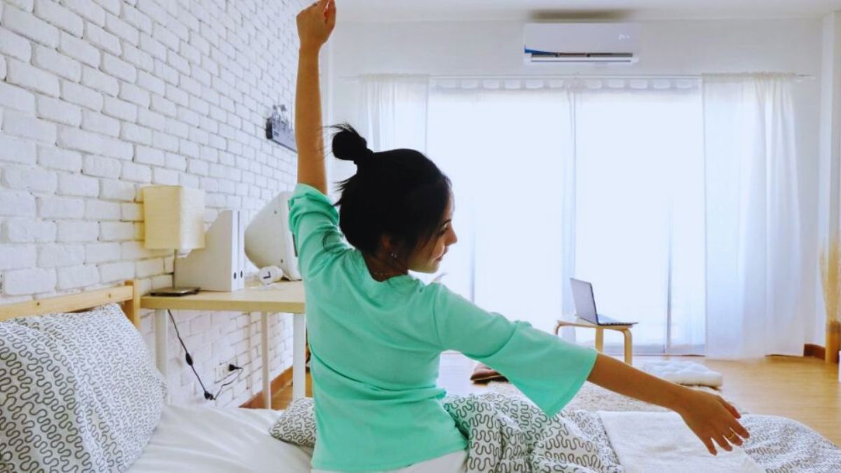 Iemand die uitgerust wakker wordt in een lichte slaapkamer