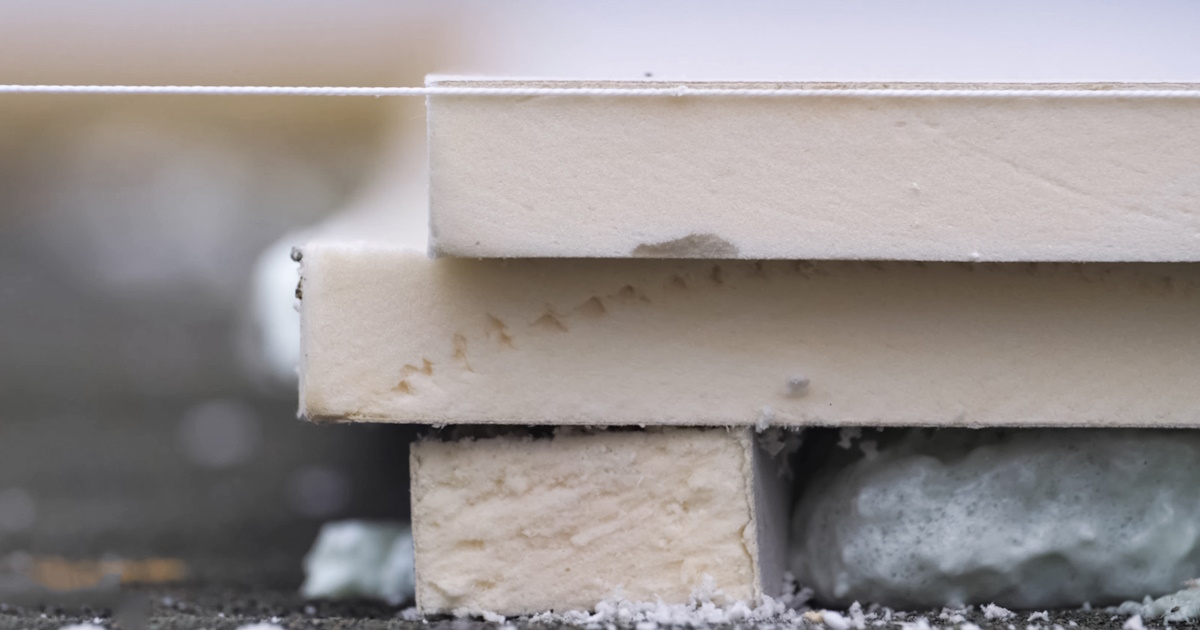 De zijkant van drie isolatieplaten met een lichte kleur. Met een touwtje wordt bekeken of de platen waterpas liggen