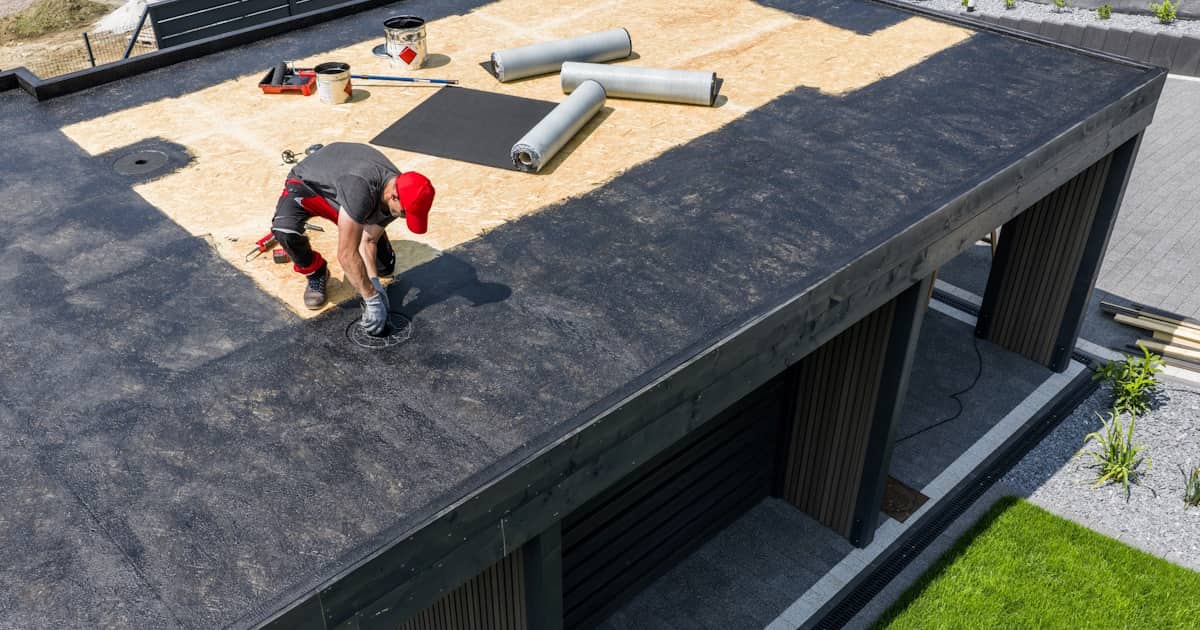 Een dakdekker maakt een plat dak gereed voor een laag EPDM dakbedekking