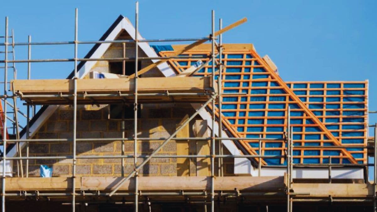 Een dak dat men aan het verhogen is. Het dak is omringd met steigers en de tengel- en pannenlatten zijn zichtbaar, met daaronder een blauw onderdak.