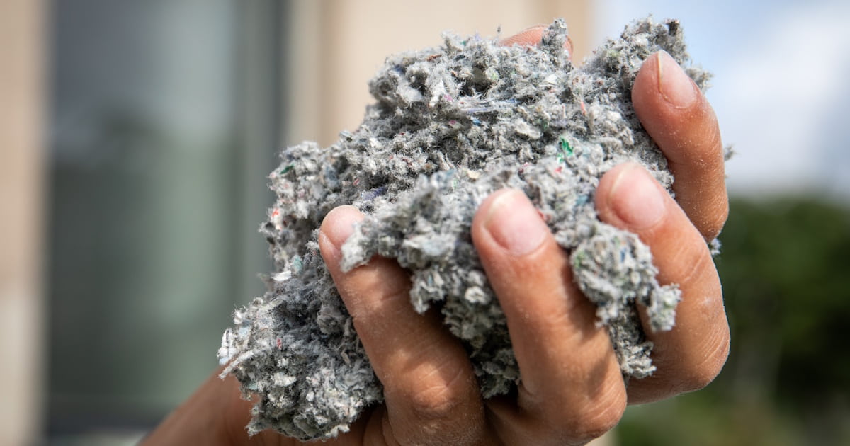 Een hand gevuld met spouwmuurisolatie. De vezelige structuur van het materiaal isgoed zichtbaar