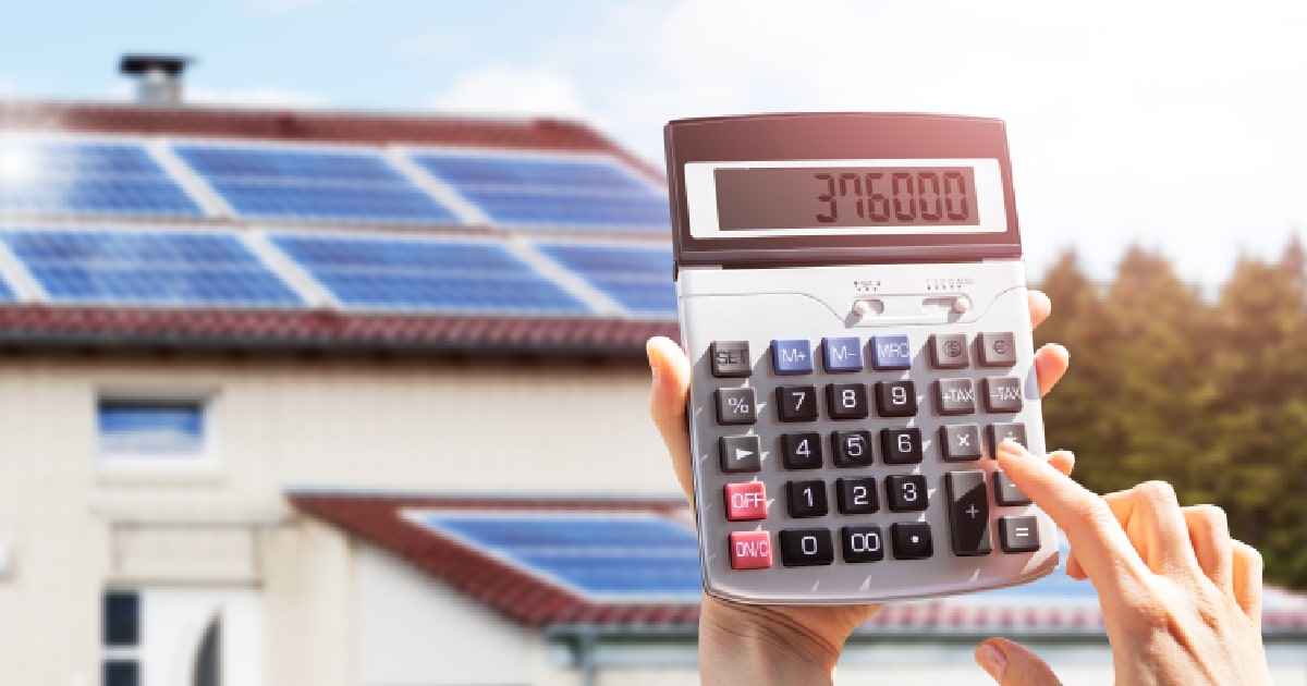 Een dame berekent het rendement of energieverlies van haar zonnepaneelinstallatie en thuisbatterij met een rekenmachine.