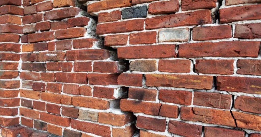 Een flinke diagonale scheur in een bakstenen gevel. Mogelijk is er sprake van een constructieve fout.