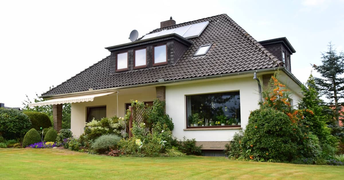 Een wit woonhuis met een kenmerkend schilddak. De dakbedekking bestaat uit grijze dakpannen.