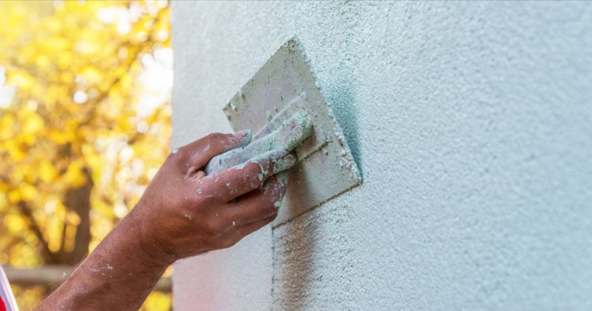 Een vakman brengt minerale sierpleister aan op een buitenmuur