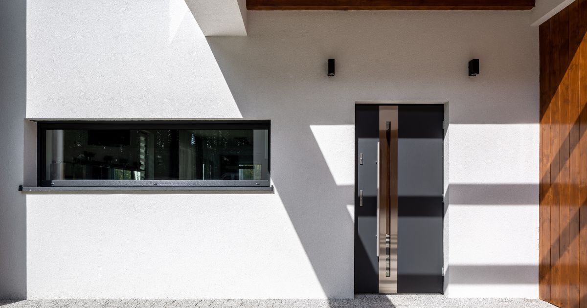 Een sierpleister gevel wordt gecombineerd met houten en metalen elementen voor een modern effect.