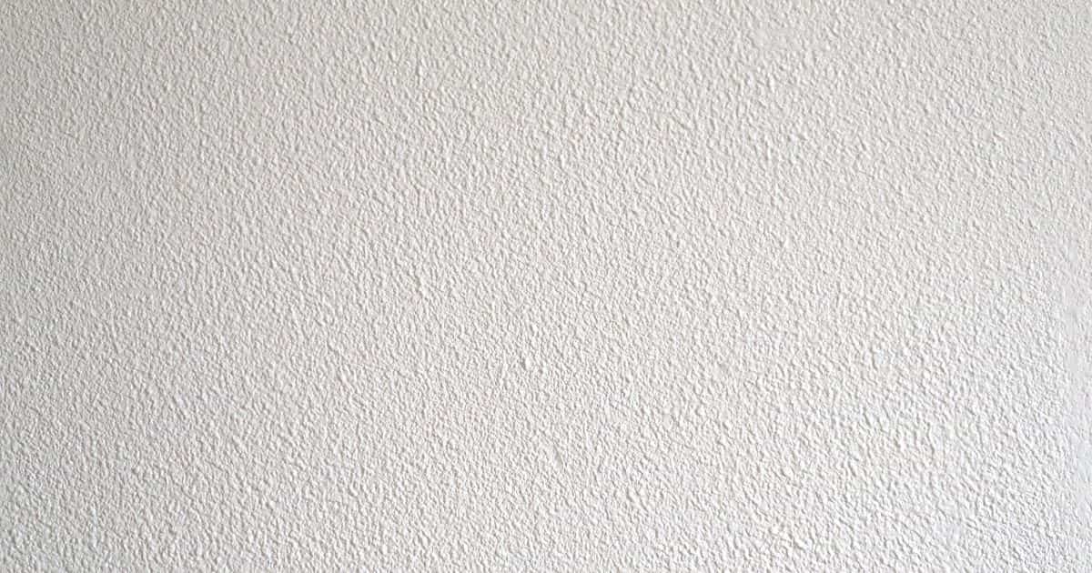 Een close-up van een witte sierpleister gevel. Van dichtbij is de structuur door de korrelgrootte goed zichtbaar.