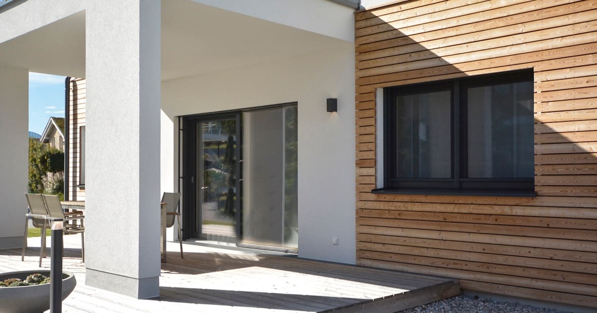 Moderne woning met wit pleisterwerk en horizontale houten gevelbekleding naast een overkapping.