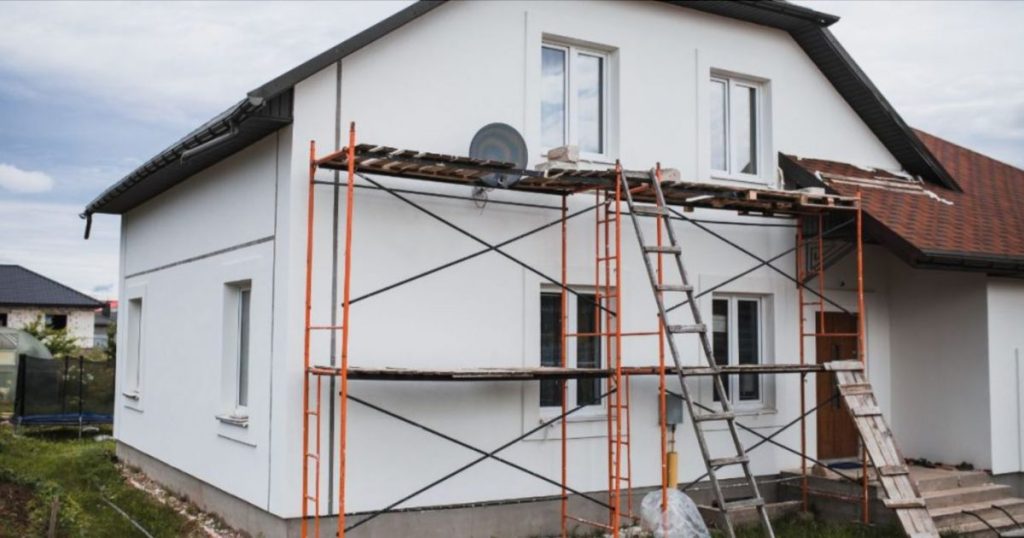 Een groot vrijstaand huis staat in de steigers, omdat er sierpleister wordt aangebracht op de gevels