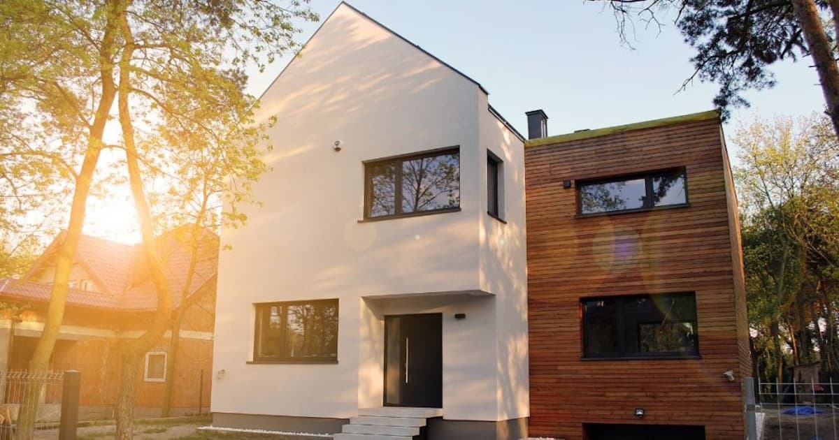 Een moderne woning waarbij de witte sierpleister gevel gecombineerd is met houten gevelbekleding.